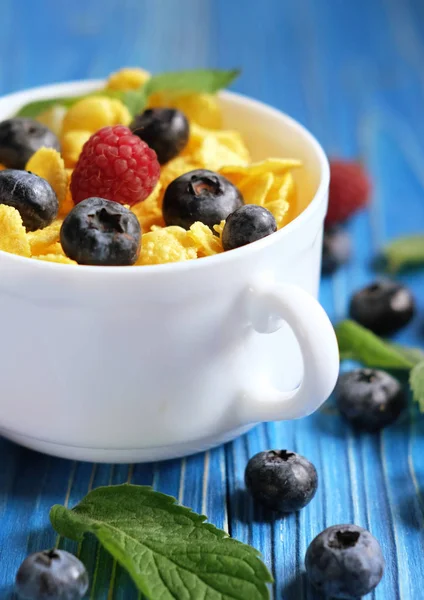 Healthy eating, food and diet concept - Cornflakes with berries raspberries and blueberries on blue wooden background. — Stock Photo, Image