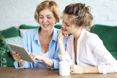 Yaşam tarzı, tehnoloji ve insanlar kavramı: evde tablet bilgisayar kullanan anne ve yetişkin kız