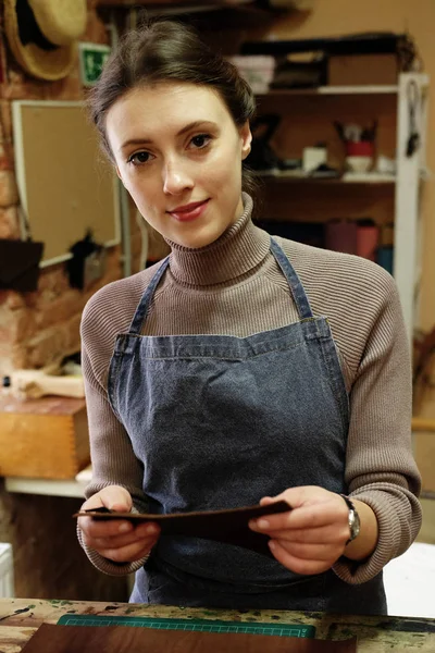 Jeune femme travaille dans un studio de fabrication de sacs, découpe les détails — Photo