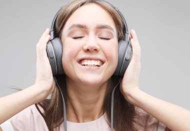 Kulaklıklı genç bir kadın müzik dinliyor.