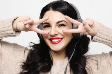  gülümseyerek kameraya bakarak ve barış işaret parmaklarıyla gösteren kadın