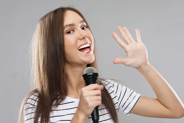 Schoonheid model meisje zangeres met een microfoon op lichte grijze achtergrond — Stockfoto