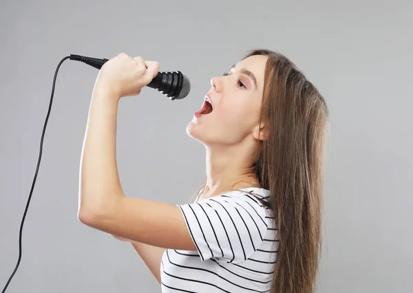 Schoonheid model meisje zangeres met een microfoon op lichte grijze achtergrond — Stockfoto