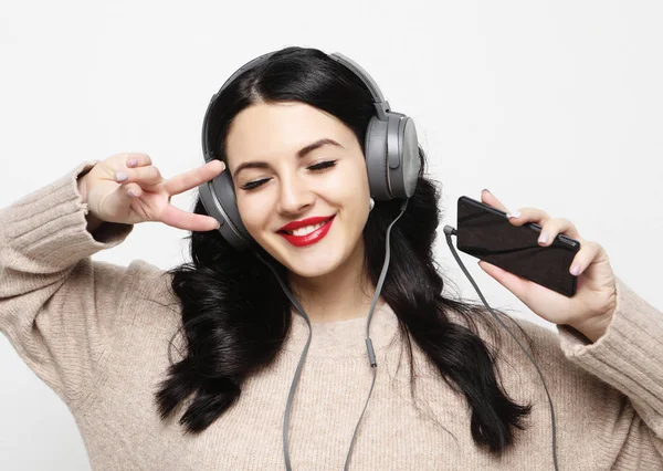 Unga kurviga brunett kvinna i hörlurar lyssna på musik — Stockfoto