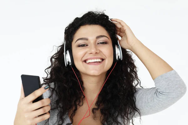 Koncepcja stylu życia i ludzi: piękna młoda kobieta słuchając muzyki w słuchawkach ze smartfonem — Zdjęcie stockowe
