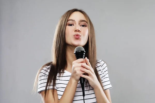 Modelo de beleza menina cantor com um microfone sobre luz cinza fundo — Fotografia de Stock