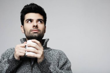 Gri arka planda kahve fincan ile yakışıklı genç sakallı adam