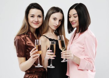 pijama giymiş üç güzel kız şampanya içmek ve eğlenmek