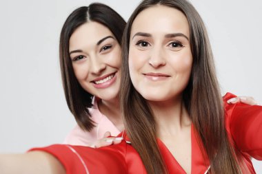 Pijama giymiş iki güzel kız kucaklaşıp selfie çekiyorlar.