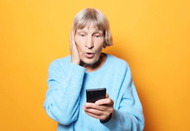 yaşam tarzı, tehnology ve insanlar kavramı: eski büyükanne onun telefon görünüyor ve şaşırır