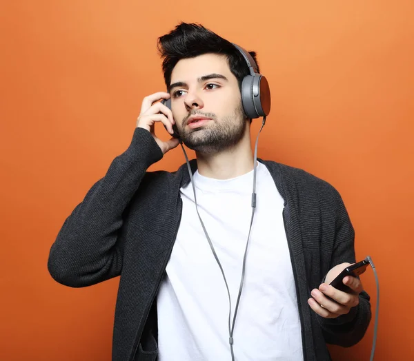 Estilo de vida, la tecnología y el concepto de la gente: Feliz joven sonriendo escuchando música en los auriculares . —  Fotos de Stock