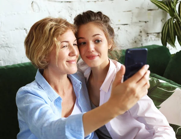 जीवनशैली, आनंद आणि लोक संकल्पना: परिपक्व आई आणि तिची मुलगी स्मार्ट फोन वापरून सेल्फी बनविते — स्टॉक फोटो, इमेज