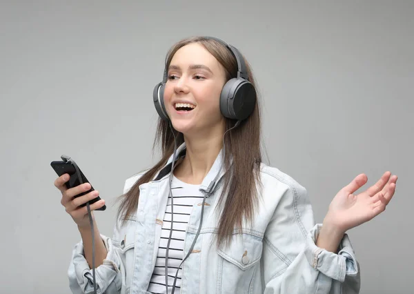 Beautiful young woman listening to music in headphones with smartphone — Stock Photo, Image