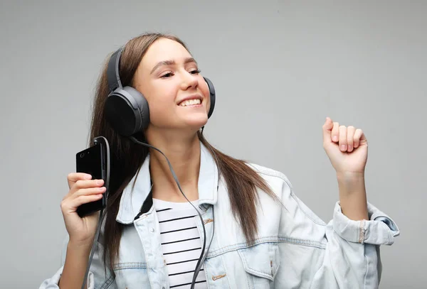 Belle jeune femme à l'écoute de la musique dans les écouteurs avec smartphone — Photo