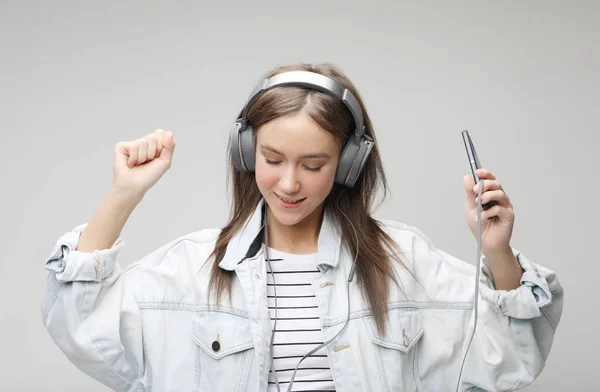 Όμορφη νεαρή γυναίκα να ακούτε μουσική στα ακουστικά με έξυπνο κινητό τηλέφωνο — Φωτογραφία Αρχείου