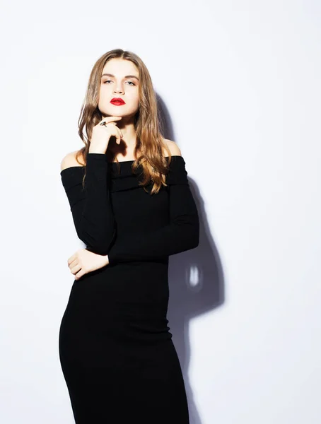 Mooie jongedame dragen zwarte jurk die zich voordeed op witte achtergrond — Stockfoto