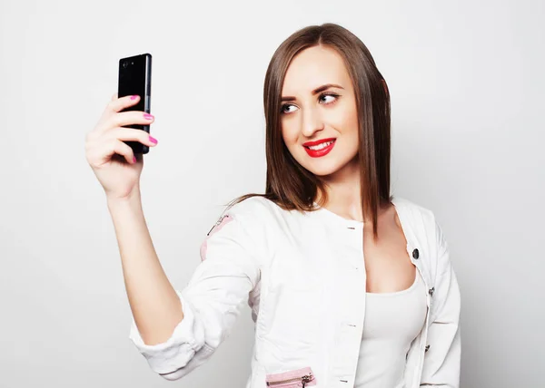 Fashion Girl ta foto gör självporträtt på smartphone bär casual över vit bakgrund — Stockfoto