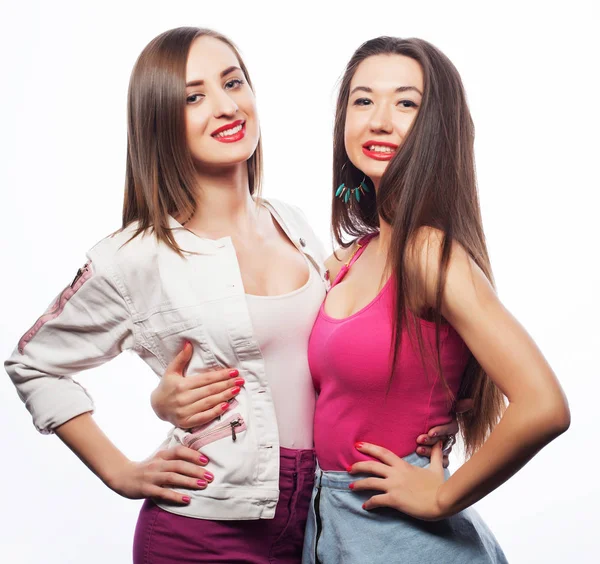 Estilo de vida y el concepto de la gente: Dos amigas jóvenes de pie juntos y divirtiéndose. Mirando la cámara. — Foto de Stock