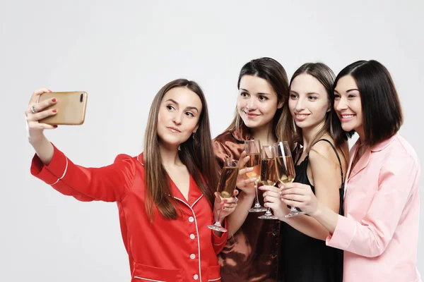 Amistad, personas, fiesta de pijama y concepto de tecnología - amigos felices o adolescentes con teléfono inteligente tomando selfie sobre fondo blanco —  Fotos de Stock