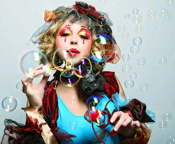 Fashion model with creative make-up blowing soap bubbles. — Stock Photo, Image