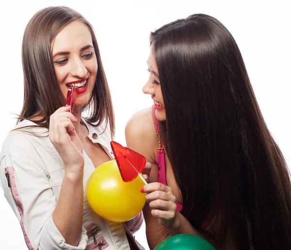 Hipster girls holding candys. Studio portrait of two cheerful best friends having fun and making funny faces — Stock Photo, Image