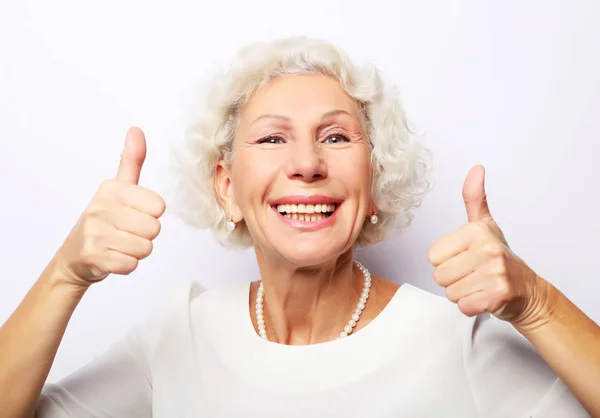 Estilo de vida, emoção e conceito de pessoas: Idosa mulher feliz dando um polegar para cima e olhando para a câmera — Fotografia de Stock