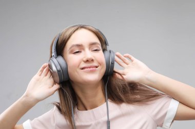 Kulaklıklı genç bir kadın müzik dinliyor.