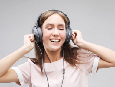 Kulaklıklı genç bir kadın müzik dinliyor.
