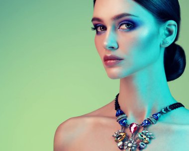 Yüksek Moda model kadın stüdyoda poz. Modaya uygun makyaj ile takı giyen güzel seksi kız Portresi