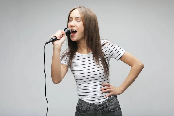 Ομορφιά κορίτσι μοντέλο τραγουδίστρια με ένα μικρόφωνο σε ανοιχτό γκρίζο φόντο — Φωτογραφία Αρχείου