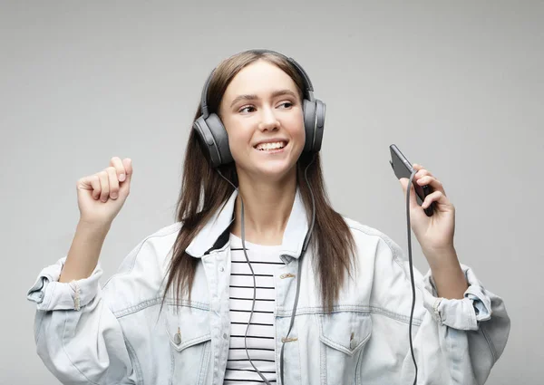 Belle jeune femme à l'écoute de la musique dans les écouteurs avec smartphone — Photo