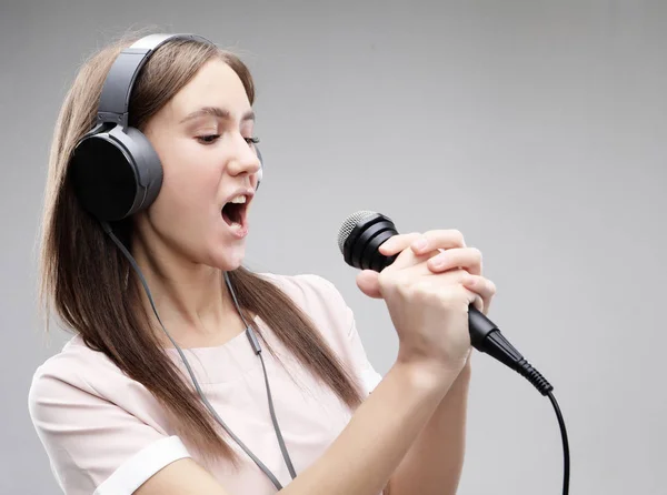 Ausdrucksstarkes Mädchen, das mit Mikrofon und Kopfhörer singt — Stockfoto