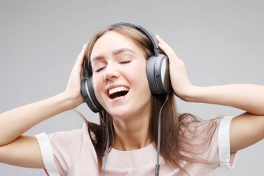Kulaklıklı genç bir kadın müzik dinliyor.