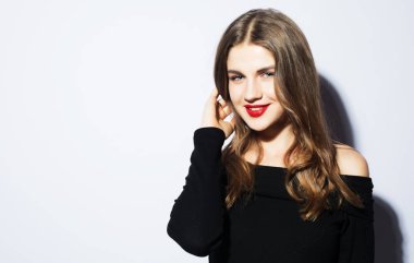 Siyah elbiseli güzel sarışın kadın beyaz arka planda poz veriyor.