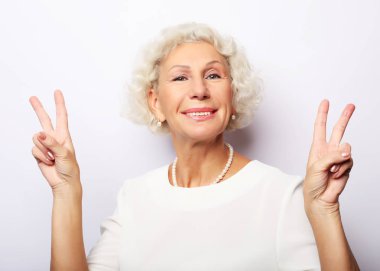 Yaşlı kadın gülmek ve kamera barış veya zafer işareti gösteren. Duygu ve duygular. Etkileyici büyükannenin portresi.