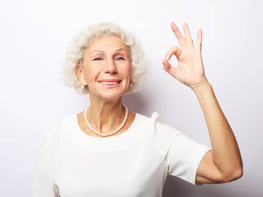 mutlu büyüleyici neşeli heyecan verici Toip gülümseme Olgun Bayan Büyükanne anneanne Büyükanne ile heyecanlı, o beyaz arka planda izole, tamam işareti gösteriyor