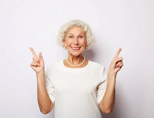 Idea, uwaga i koncepcja ludzi - portret uśmiechniętej starszej kobiety wskazującej palcem na białym tle — Zdjęcie stockowe