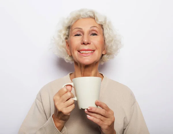 Idade animado senhora sorrindo rindo, segurando xícara beber café, chá, sobre fundo branco — Fotografia de Stock