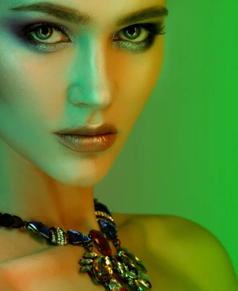 Beautiful fashion model wearing elegant jewelry in color light — Stock Photo, Image