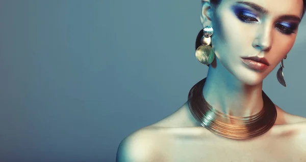 Beautiful fashion model wearing elegant jewelry in color light — Stock Photo, Image
