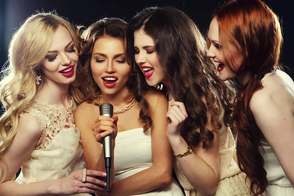 Estilo de vida, festa e conceito de pessoas quatro meninas bonitas e elegantes cantando karaoke no clube — Fotografia de Stock