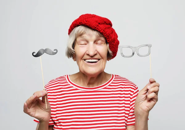 Estilo de vida e conceito de pessoas: avó engraçada com bigode falso e óculos, ri e se prepara para a festa — Fotografia de Stock