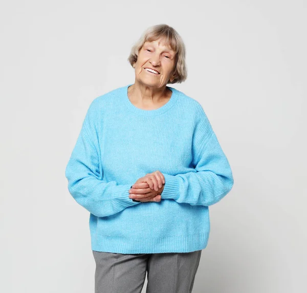 Lifestyle and people concept - portrait of a content senior lady wearing blue sweater smiling and looking at the camera — Stock Photo, Image