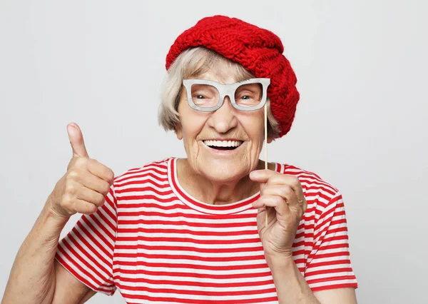 Lifestyle, emotie en people concept: grappige oma met nepbril, lacht en klaar voor het feest — Stockfoto