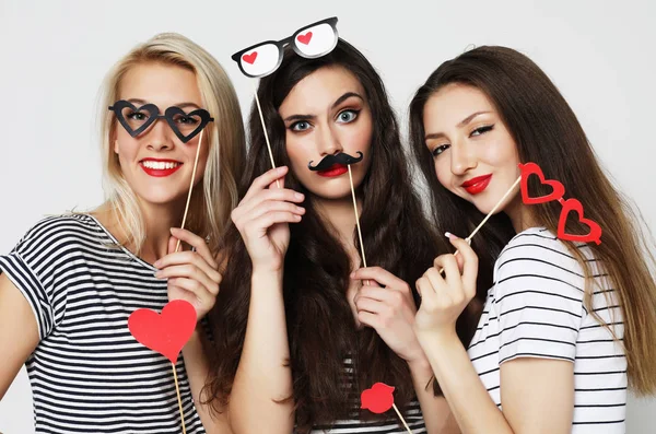 Tres mujeres jóvenes sosteniendo palos de fiesta de papel —  Fotos de Stock