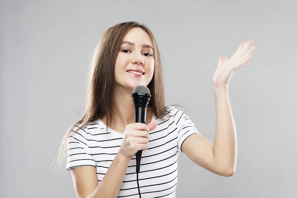 Beauty model girl singer with a microphone over light grey  background