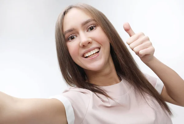 Счастливая улыбающаяся молодая женщина, делающая селфи со смартфоном — стоковое фото