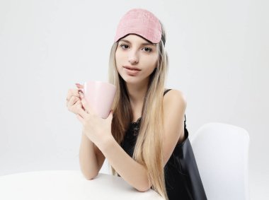 güzel kız pijama ve uyku maskesi çay veya kahve bir fincan tutan giyen