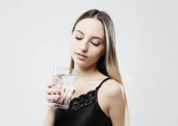 Livsstil, hälsa och människor koncept - ung kvinna bär pyjamas hålla vatten glas — Stockfoto