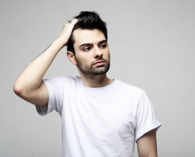 Akıllı rahat giyim yakışıklı genç esmer adam kamera bakarak, beyaz arka plan üzerinde